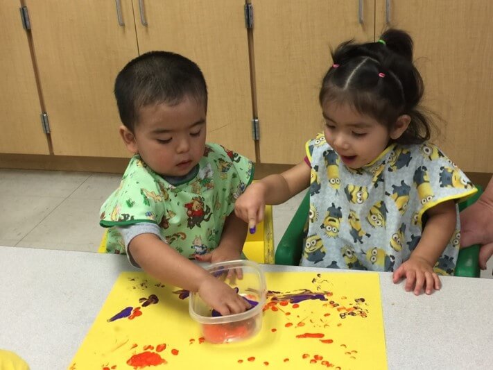 two Latine toddlers playing with paint